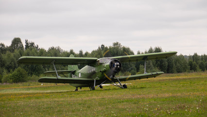 Agricultural airplane stands in a field in the green grass.