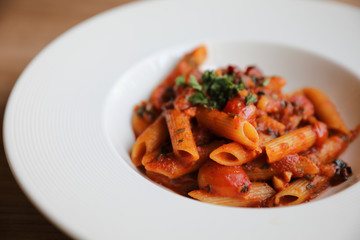 Penne arrabiata pasta tomato sauce with spices italian food on wood background
