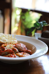 Homemade spinach Ravioli pasta with sausage in tomato sauce on wood background , italian traditional food