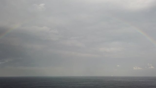 Rainbow in the ocean after rain and thunderstorms. Nice views of the rainbow against the sky, clouds and sea horizon.