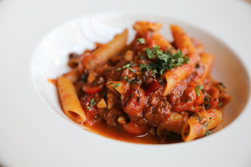 Penne arrabiata pasta tomato sauce with spices italian food on wood background