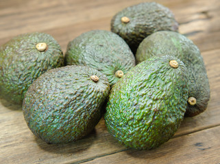 Fresh green avocados or Persea Americana on brown wooden background. Vegetarian and fruit food image.