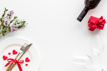 Romantic dinner on Valentines Day. Wine, plate, present box on white background top-down copy space