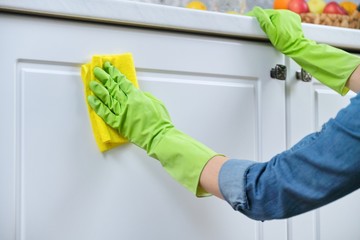 Woman in gloves with rag washing, cleaning, polishing furniture doors