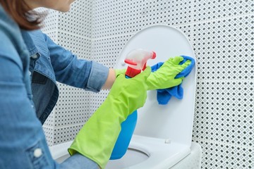 Close up of woman in gloves with rag and detergent cleaning toilet bowl