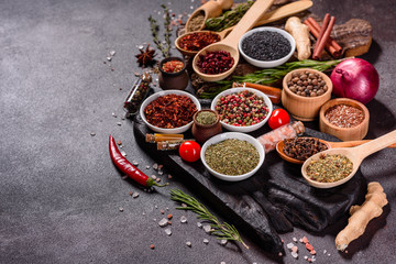 Obraz na płótnie Canvas Spices and herbs over black stone background. Top view with free space for menu or recipes