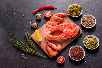 Raw trout red fish steak served with herbs and lemon and olive oil on a dark background