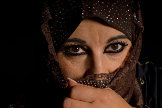 Close-Up Portrait Of Woman With Face Wrapped In Scarf Over Black Background