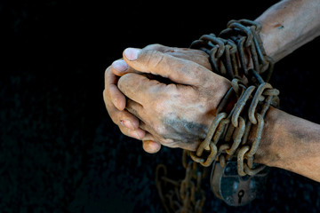 Hands of a humble slave who is not trying to free himself against a dark background
