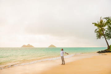 Beach vacation woman happy feeling free on Lanikai beach, Hawaii paradise honeymoon destination for USA summer travel holidays. Asian girl carefree with open arms enjoying sunshine.