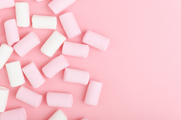 A bunch of white and pink marshmallow on a pastel light background. Colorful unhealthy sweets view from above. Pink backdrop sugar candies with copy space