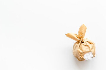 Easter gift in shape of bunny with tail on white background top-down copy space