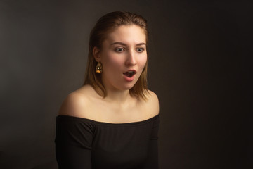 Portrait in the photo Studio of a brown-haired girl, on a black background in black clothes with open shoulders. Short hair.