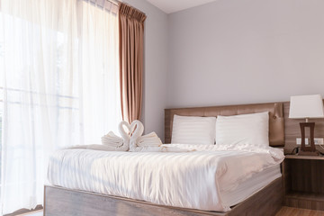 Fototapeta na wymiar Bed room with towel folded in swan shape on bed sheet