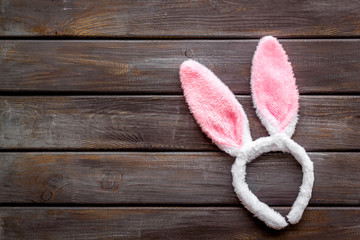 Easter bunny concept. Toy rabbit's ears for head on dark wooden background top-down copy space