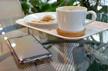 Breakfast at the cafe. On the table dirty dishes - a coffee cup and a plate - and a smartphone.