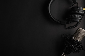 Studio black studio microphone with studio headphones on a black background. Banner. Radio, work with sound, podcasts. - 319093511