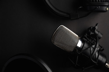 Black studio microphone on a black background with a pop filter with space for design, baner with...