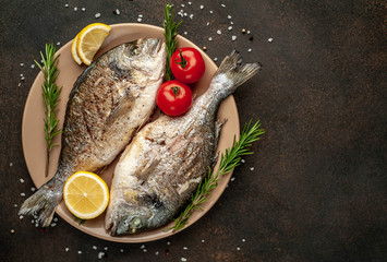 grilled dorado fish on a plate with spices and lemon on a stone background with copy space for your text
