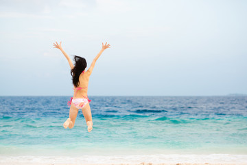 Fototapeta na wymiar 海でジャンプするビキニを着た女性