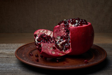 Ripe pomegranate fruit on an old black wooden vintage background.