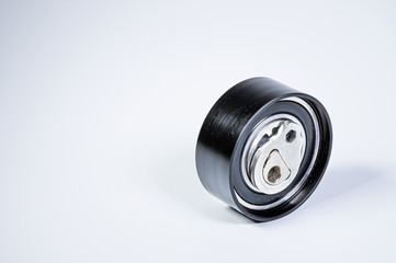 Tension roller of a timing belt of an internal combustion engine on a gray background. The concept of new spare parts and maintenance of vehicles