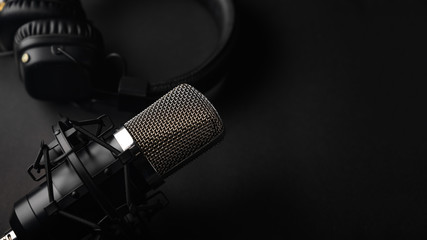 Studio black studio microphone with studio headphones on a black background. Banner. Radio, work...