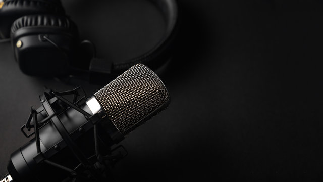 Studio black studio microphone with studio headphones on a black background. Banner. Radio, work with sound, podcasts.