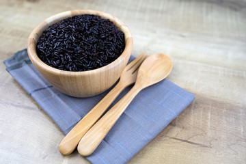 Riceberry cooked in a wooden cup Wooden spoons and wooden forks placed on fabric.