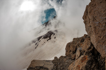 Mountain hills with the snow remnants under the sky in the white fog