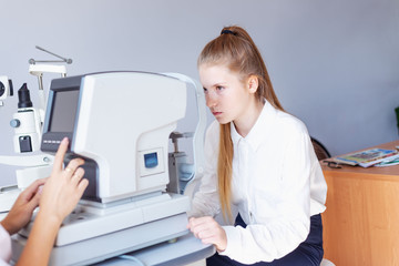An optometrist or optometrist performs diagnostics of the retina, lens of the eye and intraocular pressure on special ophthalmological equipment. schoolgirl in a white blouse