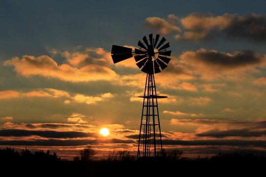 windmill at sunset with colorful cloud's and the Sun.