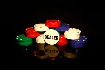 Stacks of poker chips with  dealer chip  in front isolated on black with reflections
