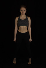 Fototapeta na wymiar Sporty girl in tops on a black background