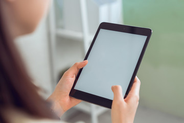 Woman hand hold tablet and digital pen with blank copy space screen for your advertisement. laptop on the table in office.
