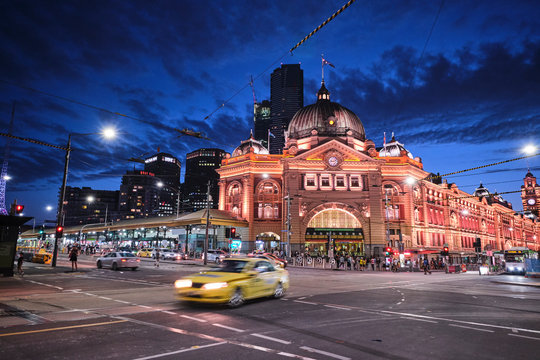 Melbourne, Victoria / Australia - January 26 2020: Flinders Street Station and church with light trails, car trails, trams, cars and tourists at blue hour