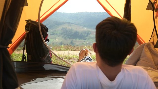 Camping man lying in orange tent. Close up of man feet wearing hiking boots. travel concept