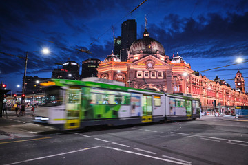Melbourne, Victoria / Australia - January 26 2020: Flinders Street Station and church with light trails, car trails, trams, cars and tourists at blue hour - obrazy, fototapety, plakaty