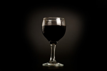 Glass with red wine shot on a dark background. Background for alcohol. Glassware for alcoholic beverages.