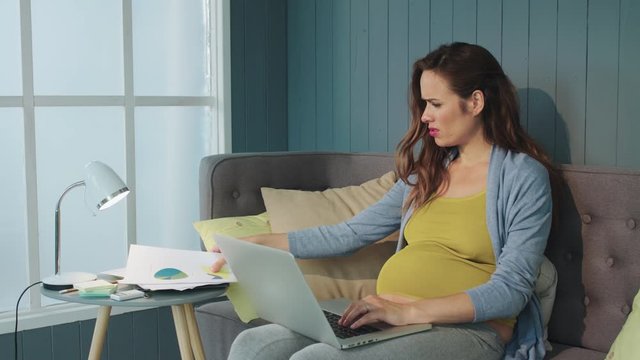 Closeup serious pregnant businesswoman hecking papers results indoors.