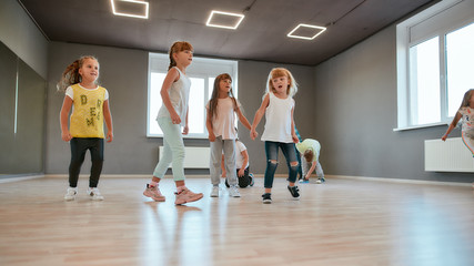 Activities for kids. Group of cute and happy children learning a modern dance in the dance studio....