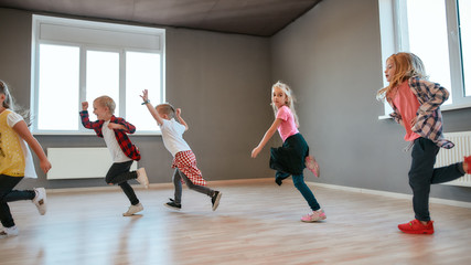 Full of energy. Little and happy boys and girls running in the dance studio. Warming up before...