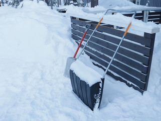 two shovels for cleaning stand in the snow near the house. Country life, winter, vacation