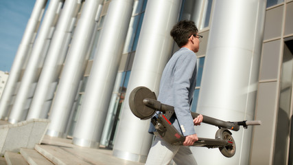 Make your route easier. Young office worker with folded e-scooter