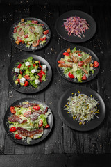 Set from different tasty,  nutritious salad of greens, cabbage, peas, carrots. Quick and easy to cook. Vegetarian food. Octoberfest party dinner. Festive table with delicious food on black boards