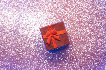 Red gift box on a shiny or glittering background. Holiday concept