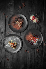 Set of desserts. Pieces of juicy delicious cakes. Festive table with delicious food on black boards.