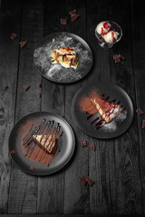 Set of desserts. Pieces of juicy delicious cakes. Festive table with delicious food on black boards.