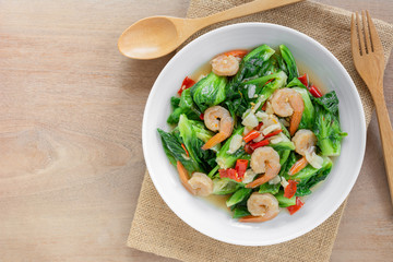 top view of stir fried cabbage sprout with shrimp in a ceramic dish on wooden table. homemade style food concept.