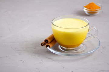 Golden milk in a glass gray cup on a gray background
